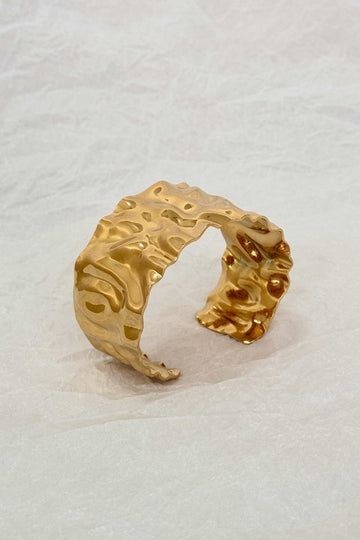 Pulseira larga em aço dourado com textura ondulada martelada