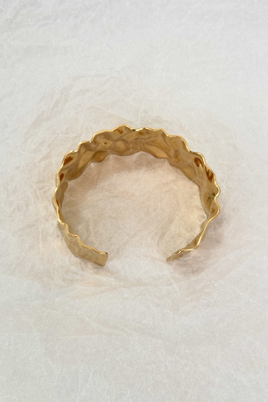 Pulseira larga em aço dourado com textura ondulada martelada