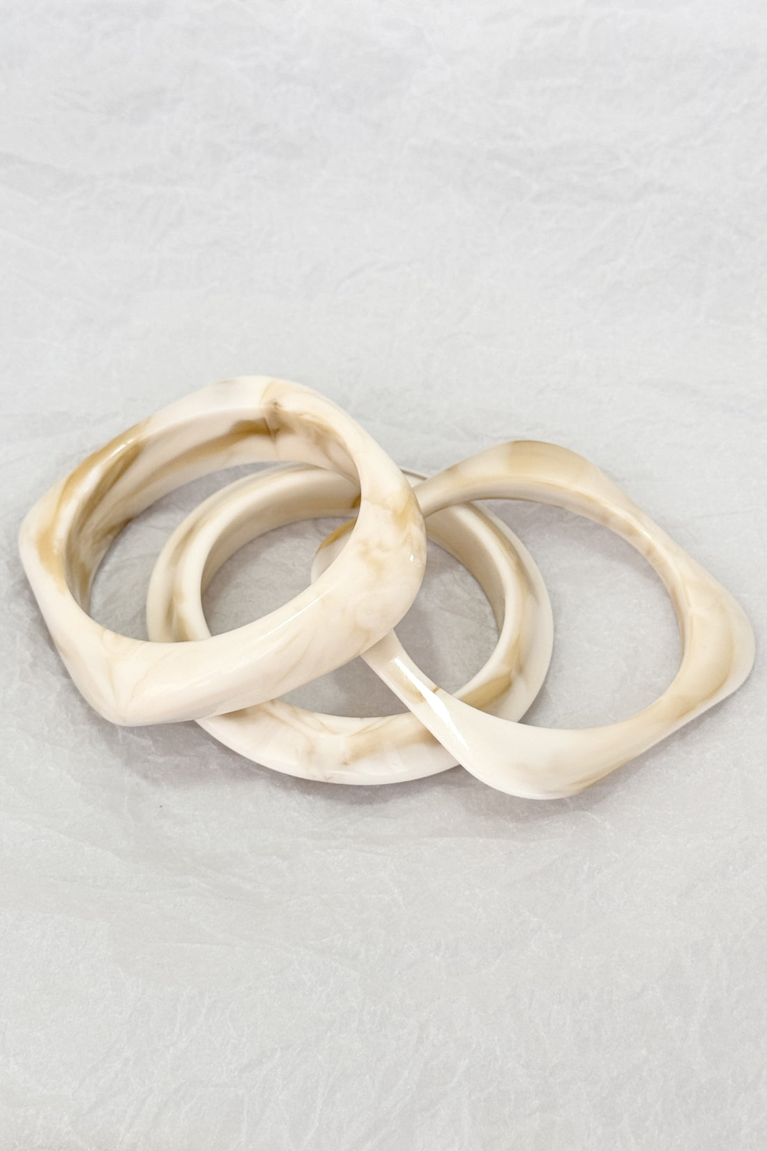 Conjunto de três pulseiras geométricas em resina com efeito mármore creme